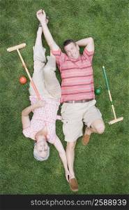 High angle view of a mature couple lying on grass in a lawn