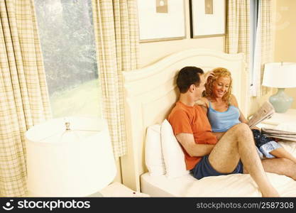 High angle view of a mature couple sitting on the bed and holding a newspaper