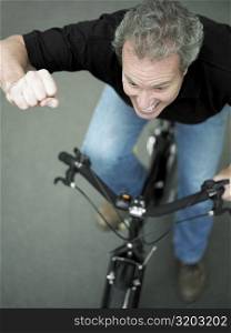 High angle view of a mature man cycling with his hand raised