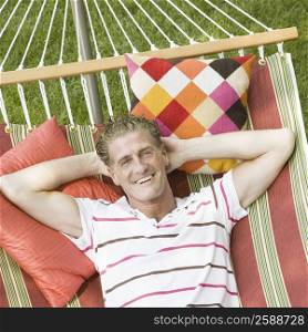 High angle view of a mature man lying in a hammock and smiling