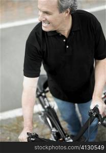 High angle view of a mature man standing with a bicycle and smiling