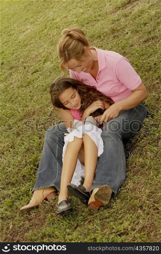 High angle view of a mature woman and her daughter reading a book in the park