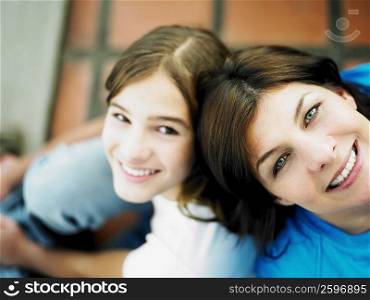 High angle view of a mature woman and her daughter sitting back to back