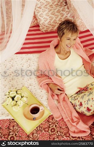 High angle view of a mature woman reclining on the bed and smiling