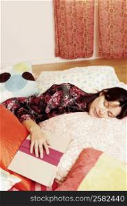 High angle view of a mature woman sleeping on the bed with a book