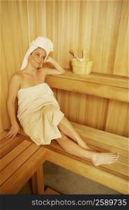 High angle view of a mature woman wearing towel sitting in a sauna