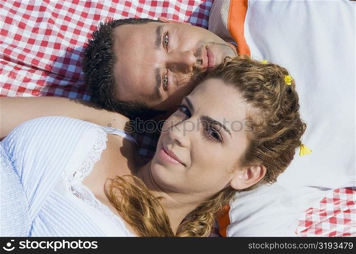 High angle view of a mid adult couple lying on a picnic blanket
