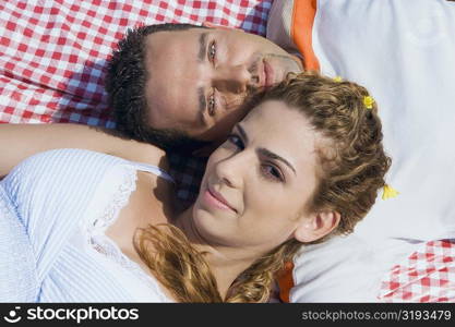 High angle view of a mid adult couple lying on a picnic blanket