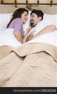 High angle view of a mid adult couple lying on the bed and looking at each other