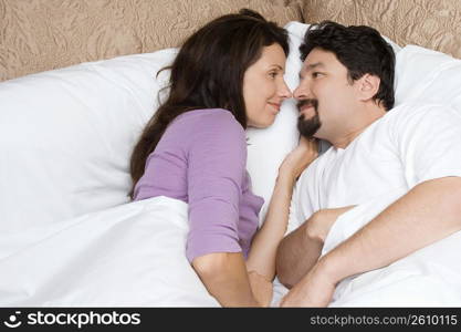 High angle view of a mid adult couple lying on the bed and looking at each other