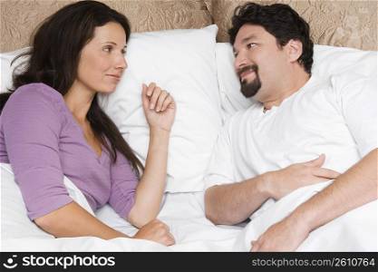 High angle view of a mid adult couple lying on the bed and looking at each other