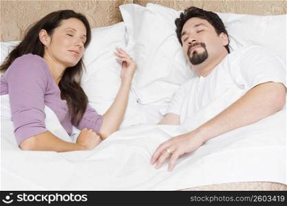 High angle view of a mid adult couple sleeping on the bed