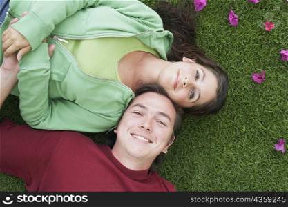 High angle view of a mid adult man and a young woman lying on the grass and smiling