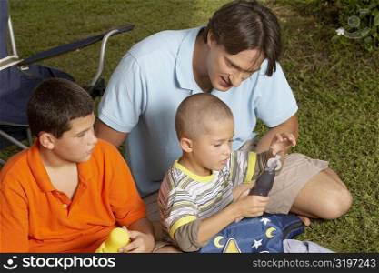 High angle view of a mid adult man and his two children sitting on the grass