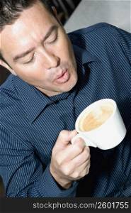 High angle view of a mid adult man blowing into a tea cup