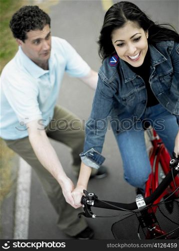 High angle view of a mid adult man helping a mid adult woman ride a bicycle