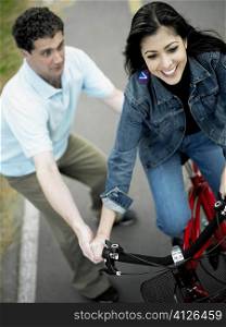 High angle view of a mid adult man helping a mid adult woman ride a bicycle