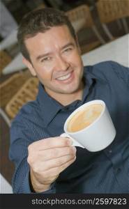 High angle view of a mid adult man holding a cup of tea in a restaurant