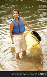 High angle view of a mid adult man holding a kayak and an oar