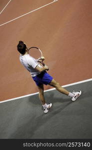 High angle view of a mid adult man holding a tennis ball and a tennis racket on a tennis court