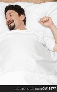 High angle view of a mid adult man lying on the bed and smiling