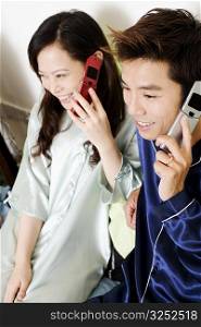 High angle view of a mid adult man with a young woman using mobile phones