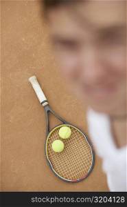 High angle view of a mid adult man with two tennis balls and a tennis racket