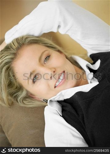 High angle view of a mid adult woman lying on a couch and smiling