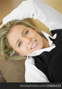 High angle view of a mid adult woman lying on a couch and smiling