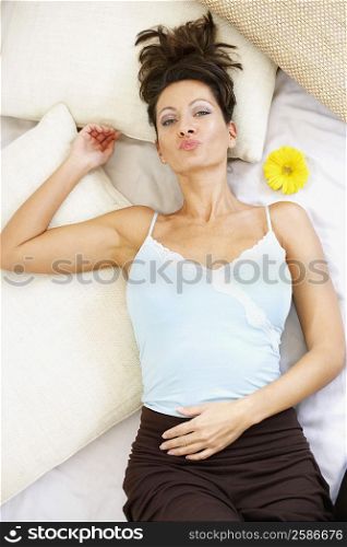 High angle view of a mid adult woman lying on the bed and puckering