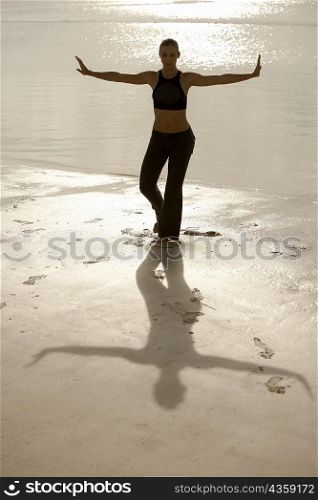 High angle view of a mid adult woman standing in the tree pose on the beach