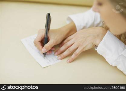 High angle view of a mid adult woman writing on a sheet of paper