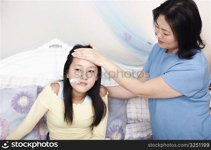 High angle view of a mother&acute;s hand on her daughter&acute;s forehead