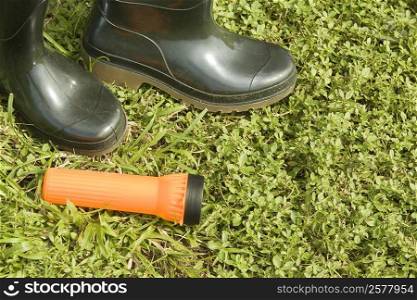 High angle view of a pair of boots with a flashlight on the grass