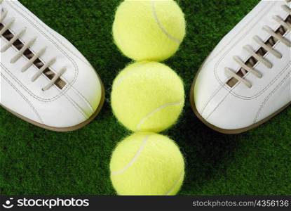 High angle view of a pair of sports shoes and three tennis balls