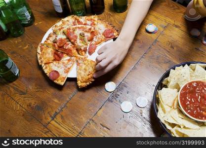 High angle view of a person&acute;s hand picking up a pizza slice