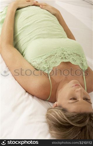 High angle view of a pregnant woman lying on the bed touching her abdomen