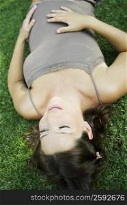 High angle view of a pregnant young woman lying on the grass and touching her abdomen