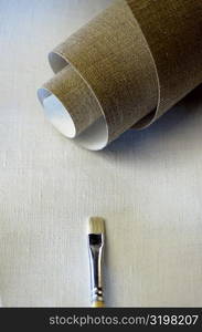 High angle view of a roll of canvas and a paintbrush