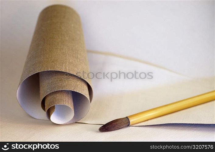 High angle view of a roll of canvas and a paintbrush