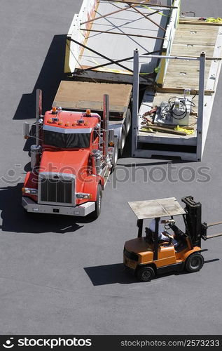 High angle view of a semi-truck and a forklift at a commercial dock