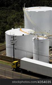 High angle view of a semi-truck on the road with storage tanks in the background