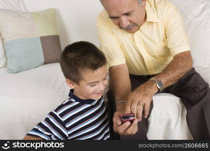 High angle view of a senior man showing a mobile phone to his grandson