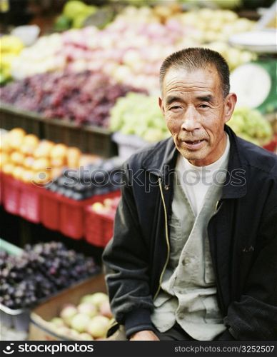 High angle view of a senior man sitting in front of a vegetable stand