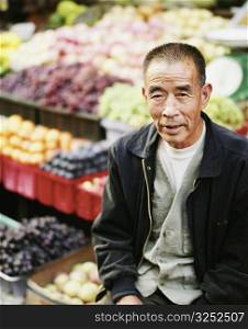 High angle view of a senior man sitting in front of a vegetable stand
