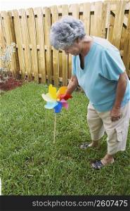 High angle view of a senior woman fixing a pinwheel in a lawn