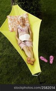 High angle view of a senior woman lying in a hammock and smiling