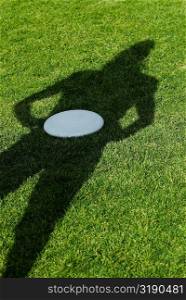 High angle view of a shadow of a person with a plastic disc in a park