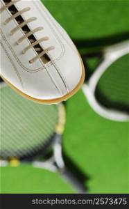 High angle view of a sports shoe with two tennis rackets