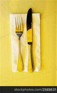 High angle view of a table knife with a fork on a napkin
